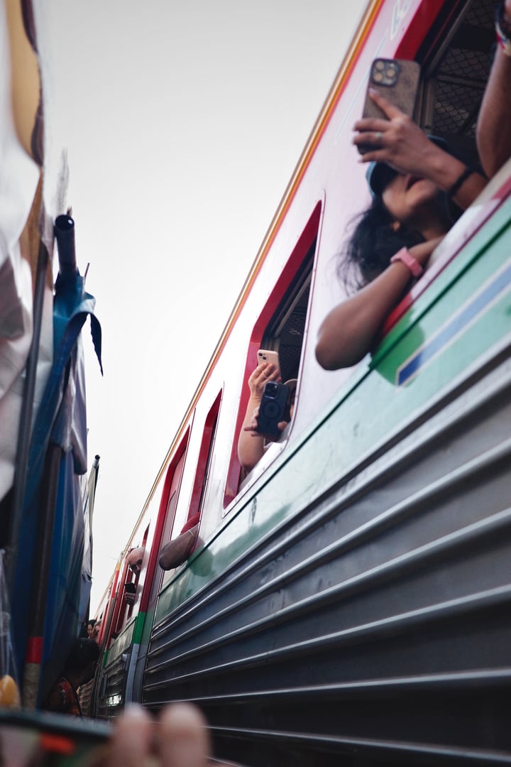 A colorful train car is seen with people inside, some holding up their phones to capture the moment.