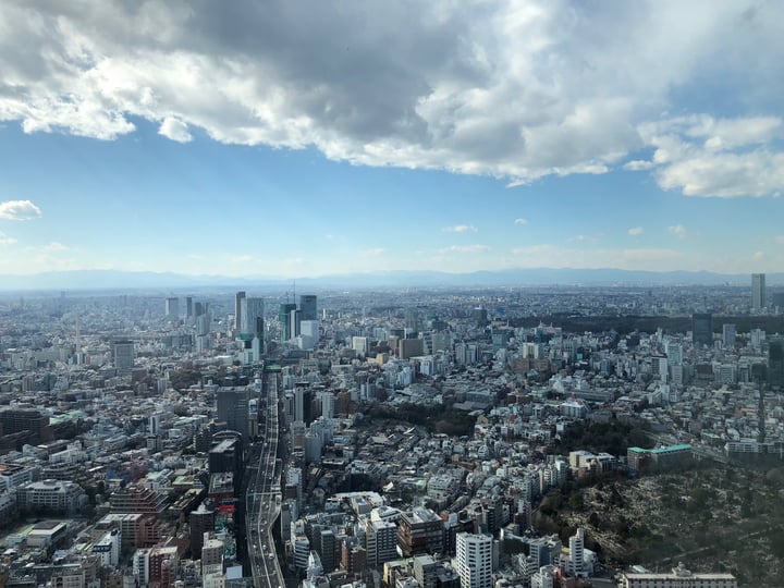A bustling cityscape with towering skyscrapers and a large river in the background.
