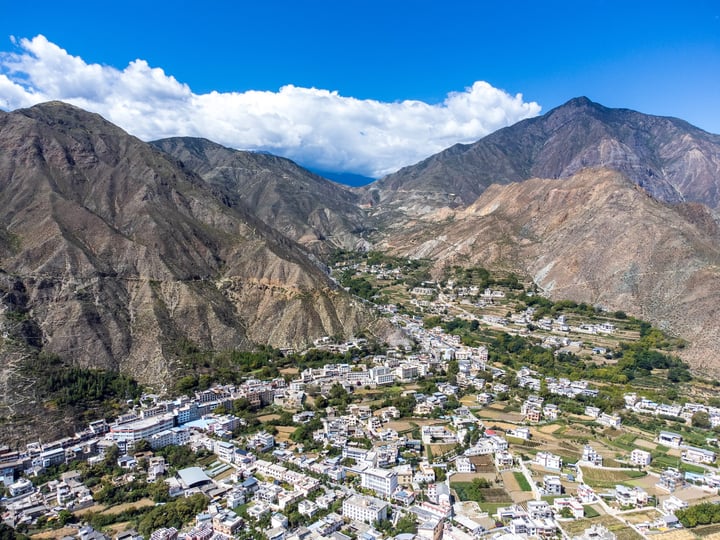 A picturesque mountain town nestled in the mountains, surrounded by lush greenery and a clear blue sky.
