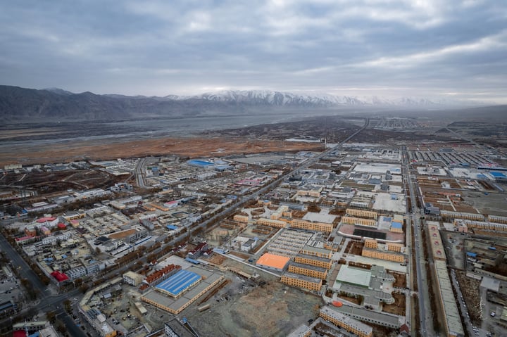 An aerial view of a city with a mix of buildings, roads, and mountains in the background.