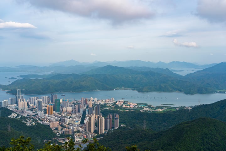 A panoramic view of Shenzhen's cityscape, with tall buildings and a large body of water, is captured from a high vantage point.