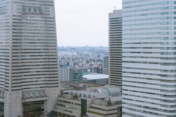 A cityscape with skyscrapers, a large building, and a few smaller ones, surrounded by a hazy sky.